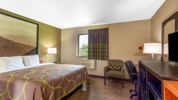 Une chambre d’hôtel équipée d’un lit, d’un bureau, d’une chaise, d’une télévision et d’une fenêtre avec des rideaux.