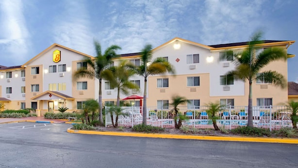 A hotel with multiple floors, a swimming pool, and palm trees. - Super 8 by Wyndham Clearwater/St. Petersburg Airport (Clearwater)