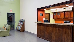 A reception area with a wooden counter, a seating area with a sofa, and a magazine rack. - Super 8 by Wyndham Clearwater/St. Petersburg Airport (Clearwater)