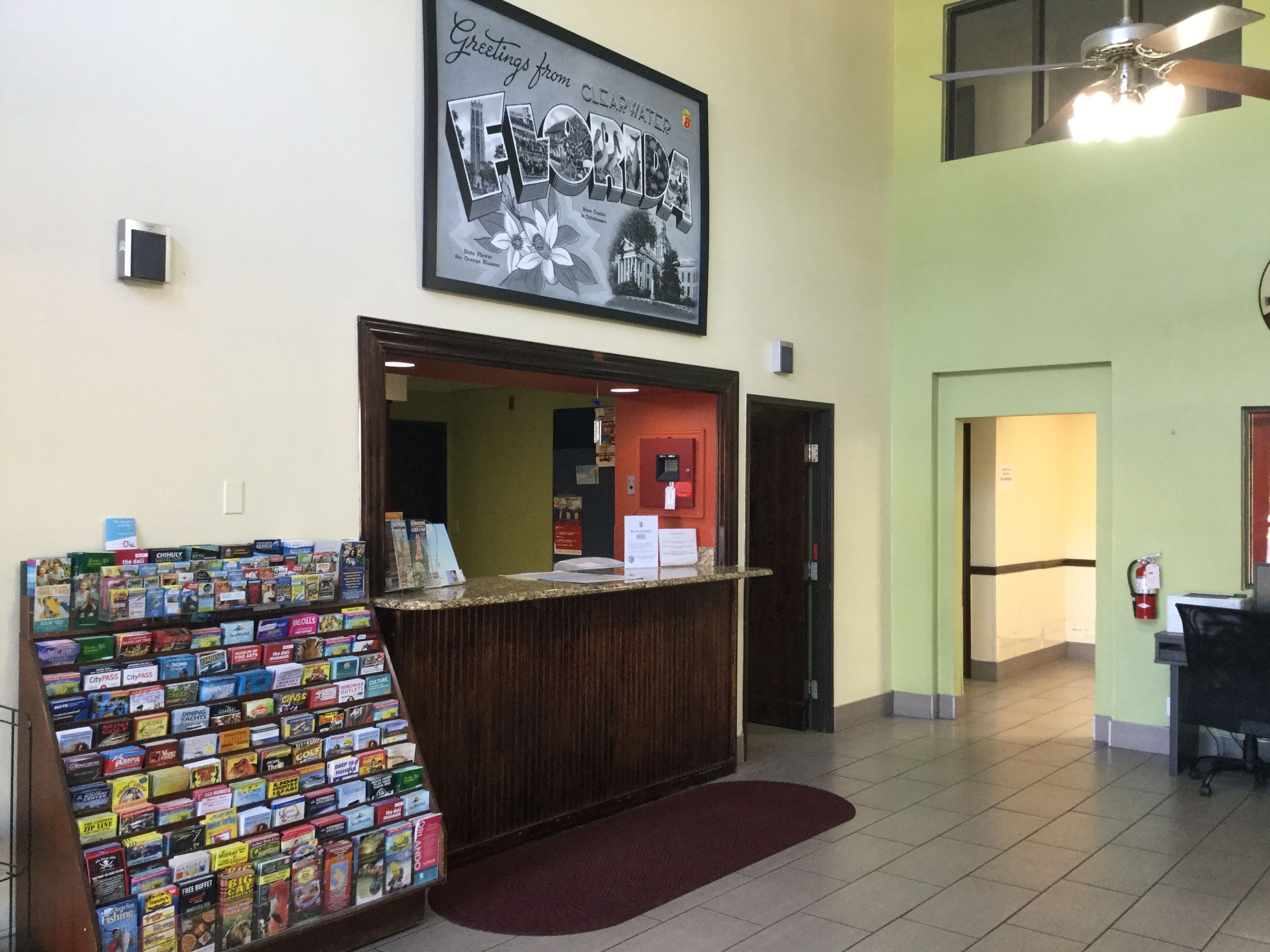 A reception area with a counter displaying various board games, a framed welcome sign, and a ceiling fan.