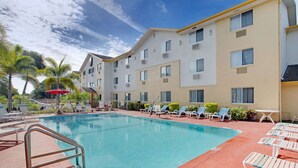 A swimming pool with lounge chairs and a building with multiple windows. - Super 8 by Wyndham Clearwater/St. Petersburg Airport (Clearwater)