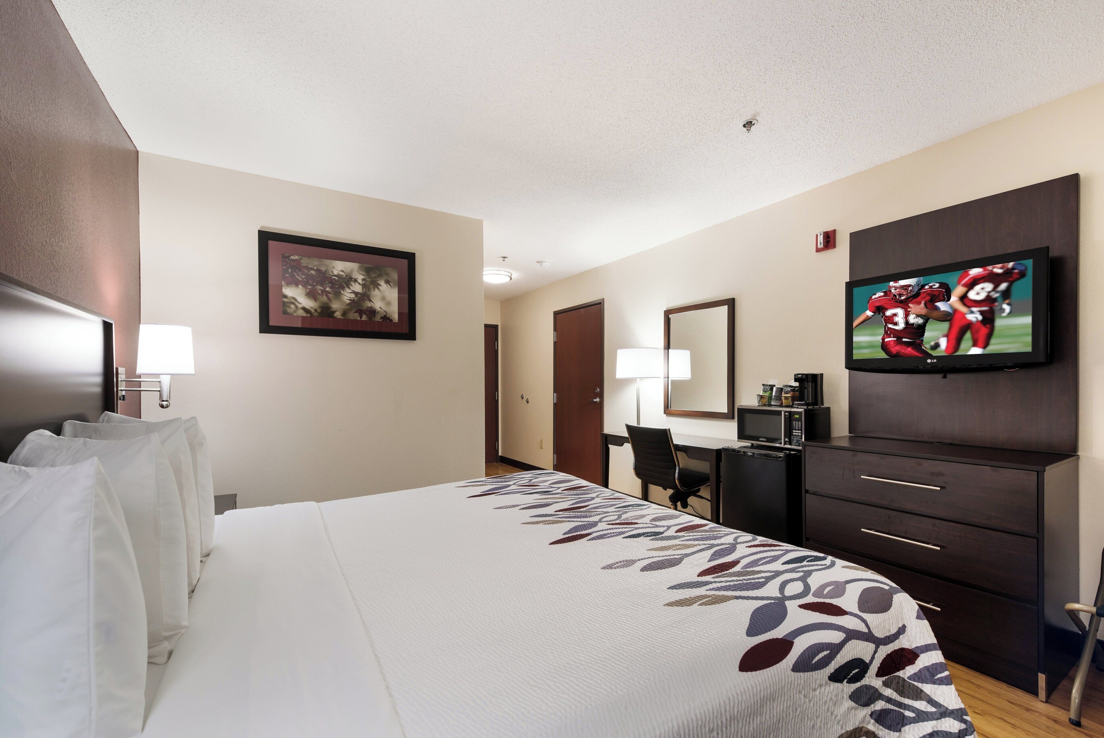 A hotel room with a bed, a desk, a television, and a wardrobe.