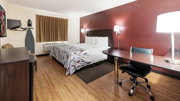 Une chambre d’hôtel équipée d’un lit, d’un bureau, d’une chaise et d’un téléviseur fixé au mur.