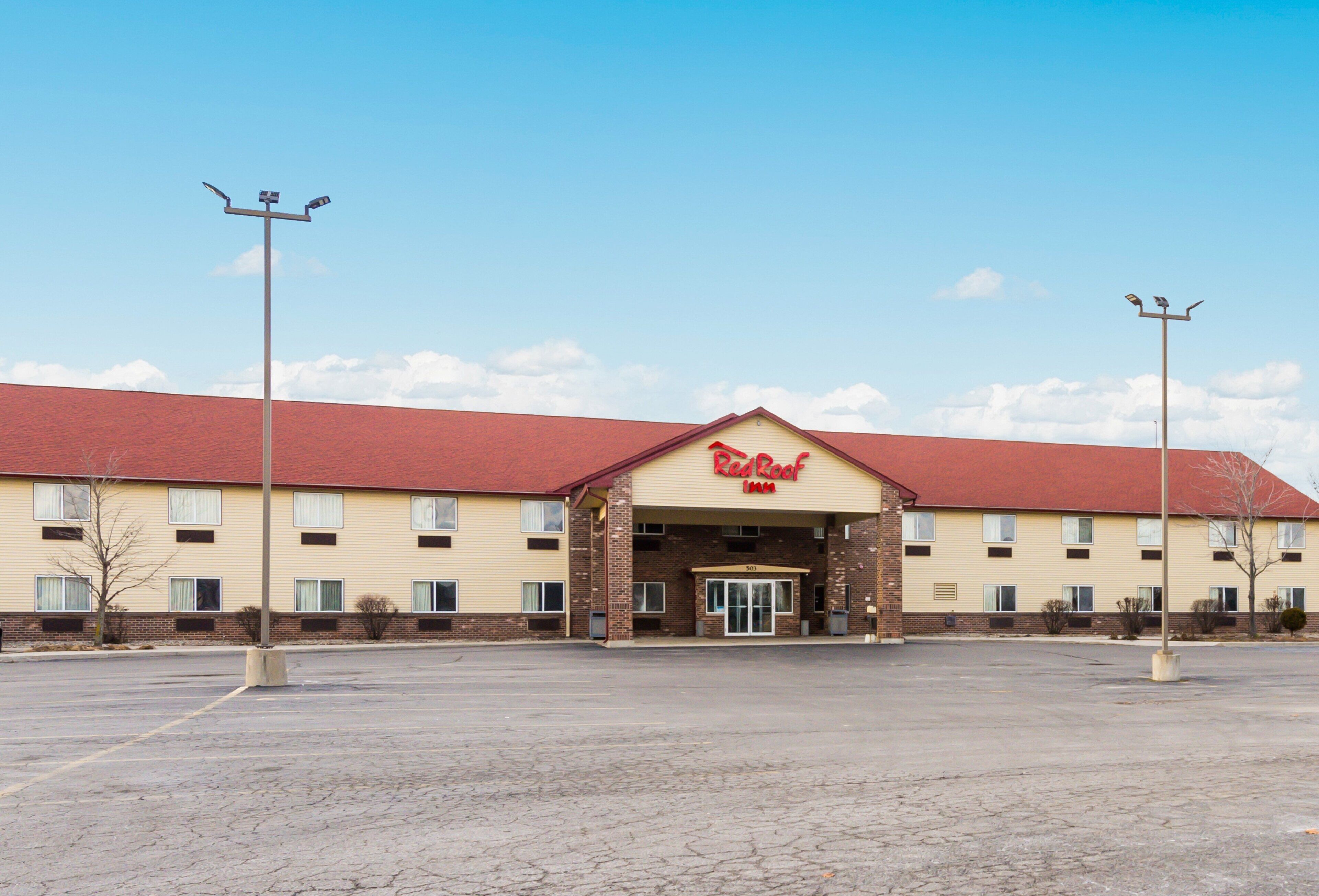 Um Red Roof Inn com telhado vermelho, paredes bege e entrada de tijolos.