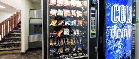 Una máquina expendedora con diversas opciones de bocadillos y una máquina de Coca-Cola.