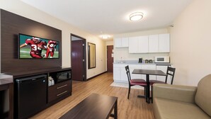 Un espace de vie compact comprenant un téléviseur à écran plat, une kitchenette, un coin repas et un canapé.