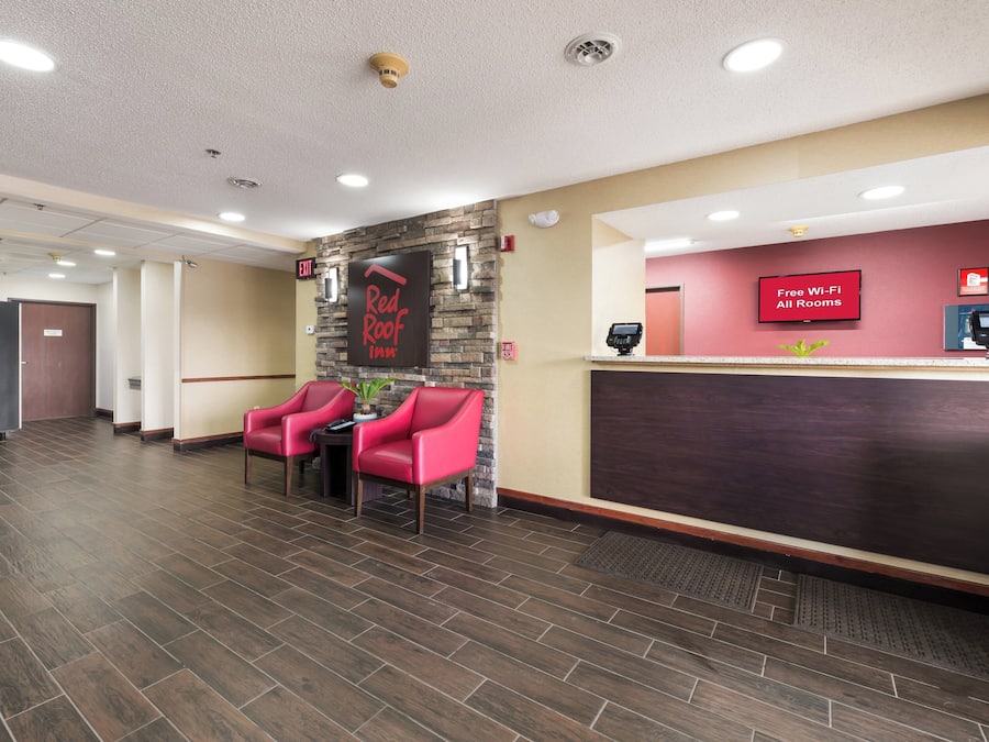 A hotel reception area with a Red Roof Inn sign, a fire alarm, and a free Wi-Fi sign.