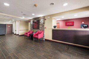 Zona de recepción de un hotel con un letrero de Red Roof Inn, un detector de incendios y un cartel de Wi-Fi gratuito.