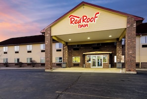 Un Red Roof Inn con fachada de ladrillo, entrada cubierta y estacionamiento.