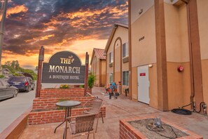 The exterior of The Monarch Boutique Hotel with a brick entrance, outdoor seating, and a view of the sky.