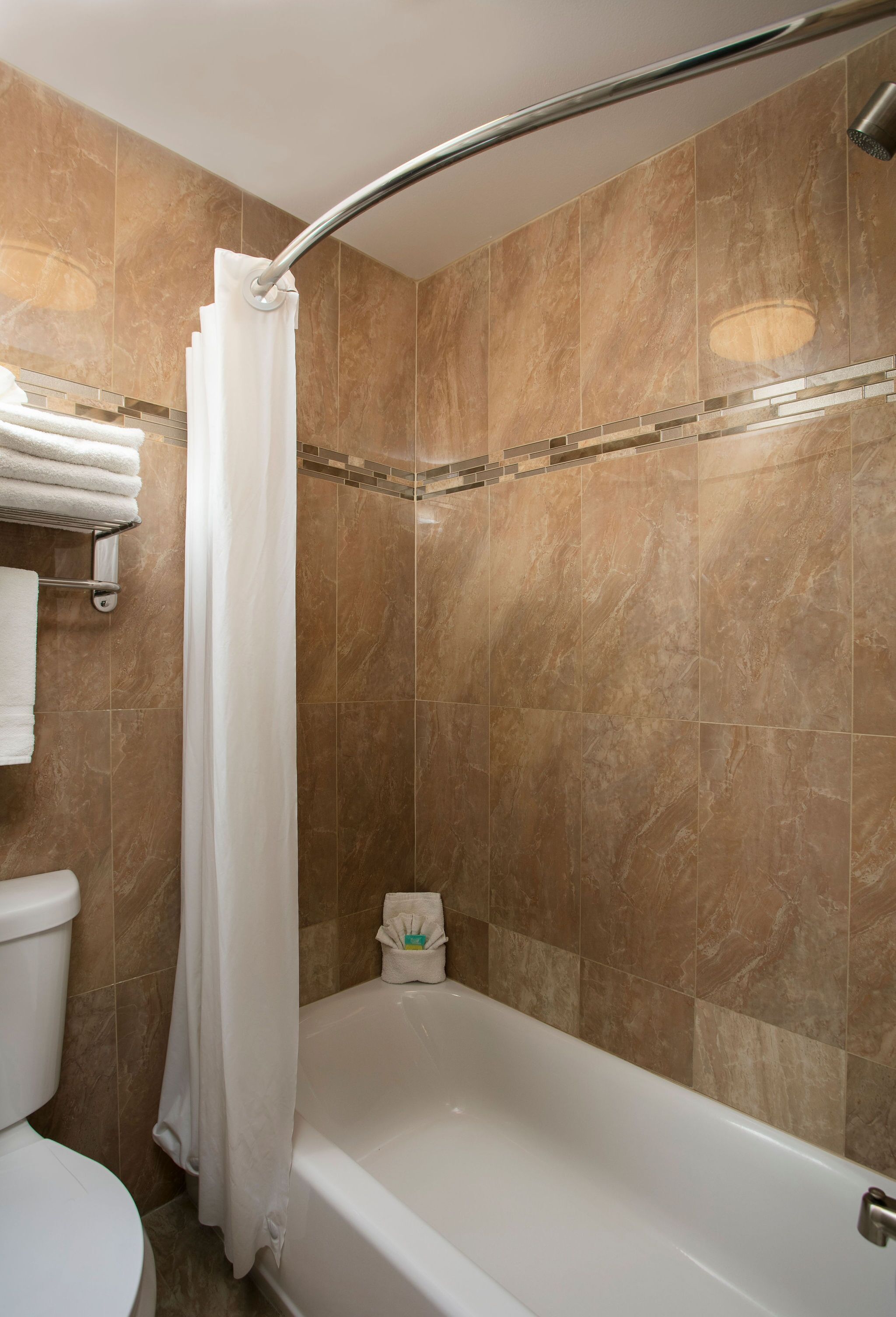 A bathroom with a bathtub, a shower curtain, and a toilet.