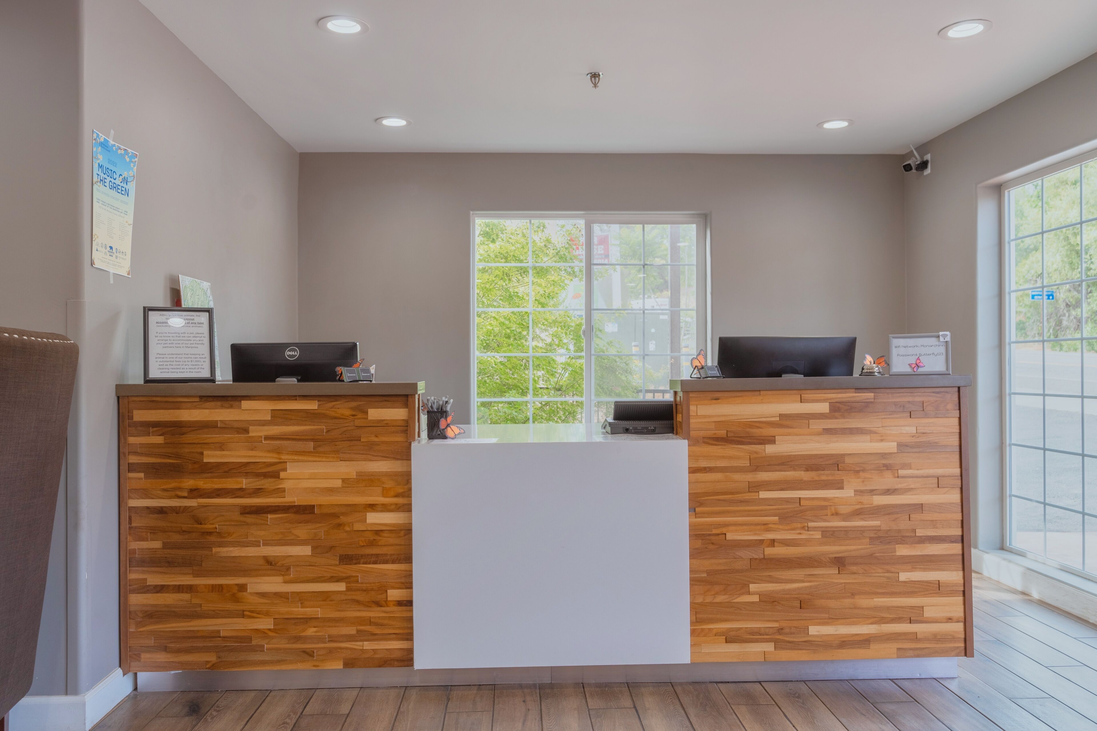 Zona de recepción con un mostrador de madera, una computadora y una pizarra.