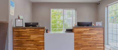 Zona de recepción con un mostrador de madera, una computadora y una pizarra.