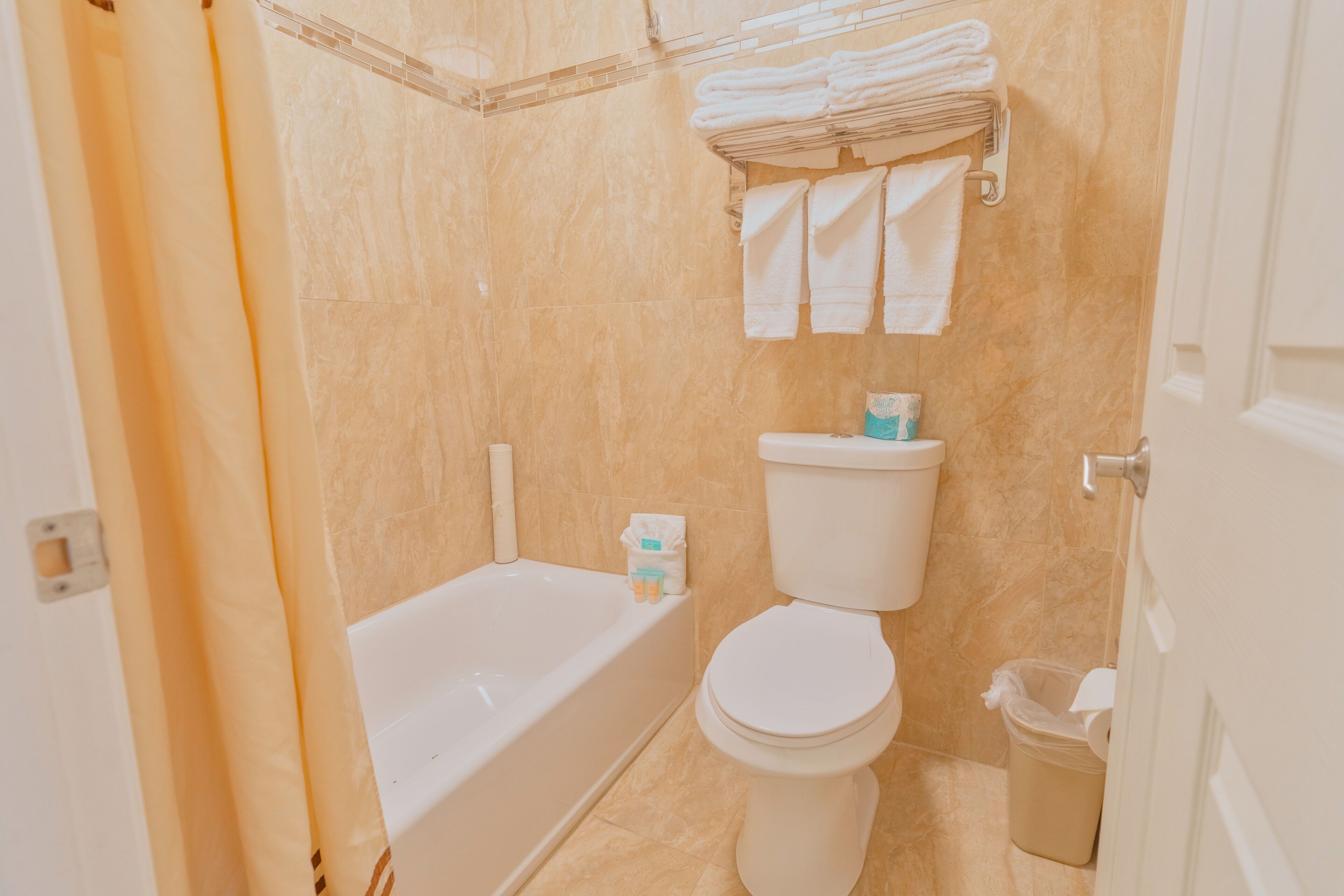 Une salle de bain équipée d’une baignoire, de toilettes et d’un porte-serviettes avec des serviettes pliées.