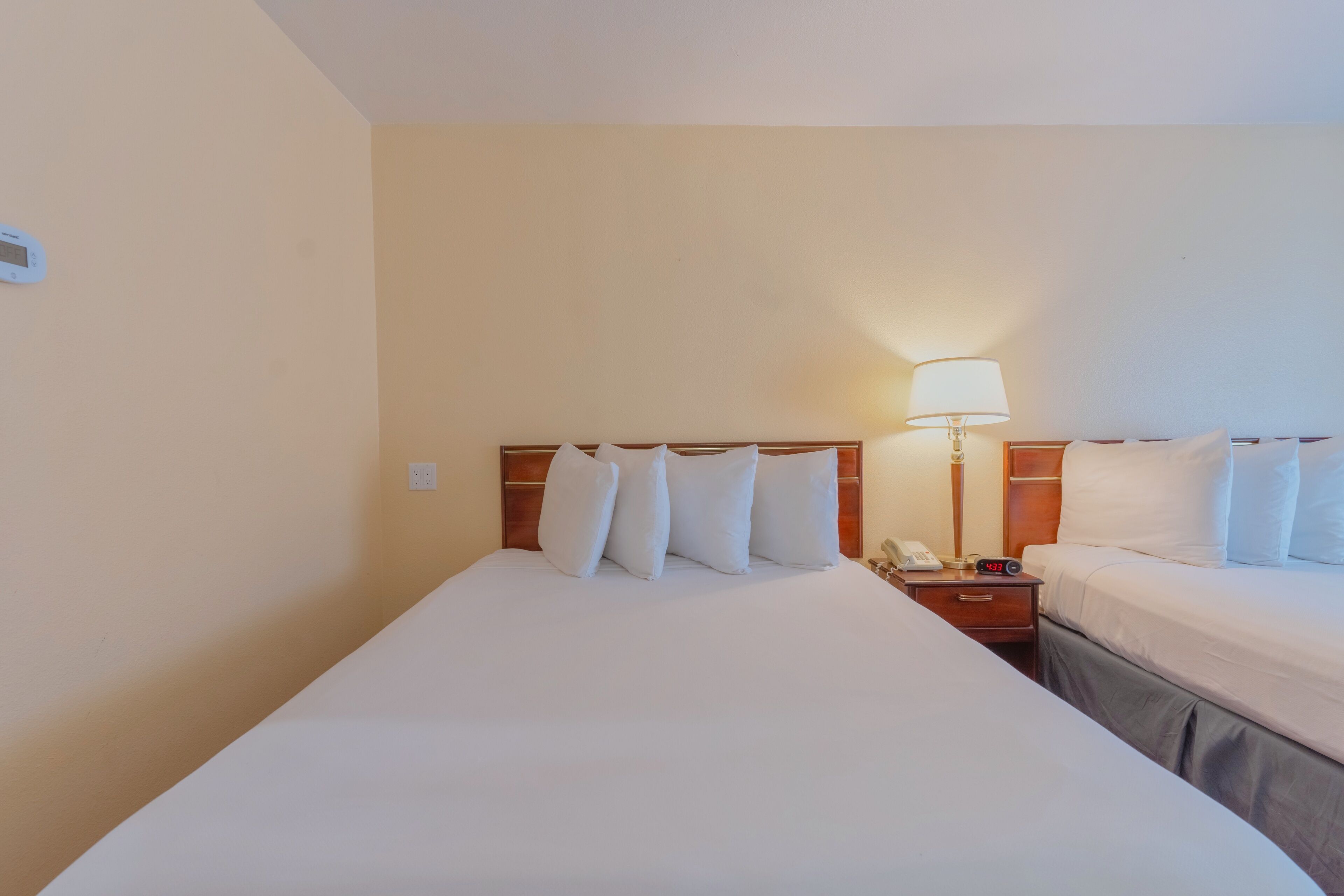 A hotel room with a large bed, two bedside tables, a lamp, and a clock.