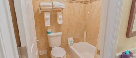 A bathroom with a toilet, a bathtub, and a shower area.