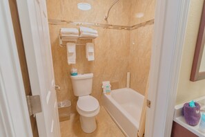 A bathroom with a toilet, a bathtub, and a shower area.