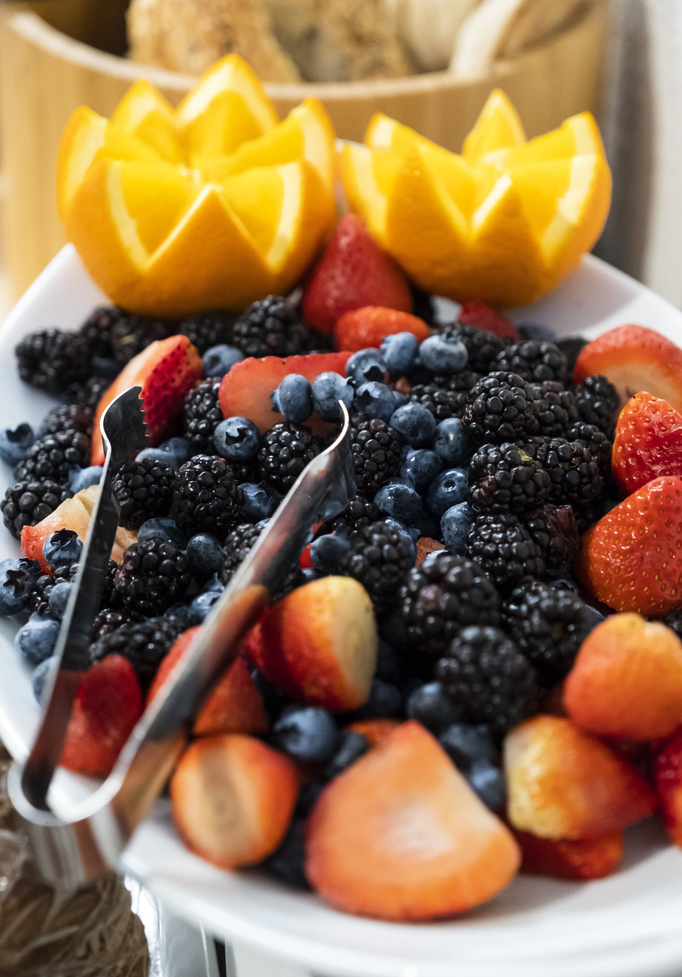 Un plato con una variedad de frutas, incluyendo fresas, arándanos, frambuesas y trozos de mango.