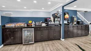 A kitchen area with a coffee station, a microwave, and a refrigerator.