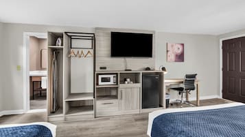 A hotel room with a bed, a desk, a television, a microwave, and a refrigerator.