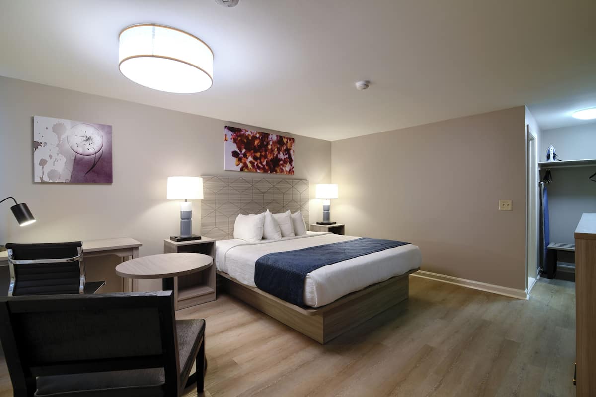 Una habitación de hotel moderna con cama, mesitas de noche, un escritorio y sillas.