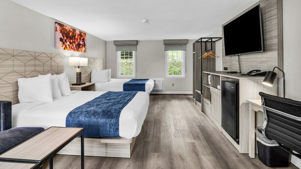 A hotel room with a bed, bedside tables, a desk, a TV, and a wardrobe.