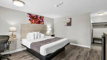 A modern hotel room with a large bed, a desk, and a chair.
