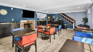 Un restaurant avec des tables et des chaises, un téléviseur et une cheminée.