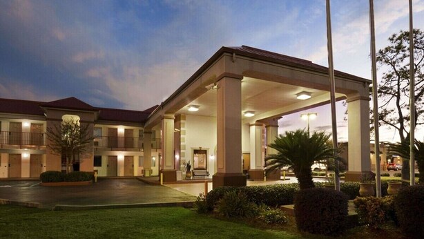 A hotel with a covered outdoor area, multiple balconies, and a well-maintained lawn.