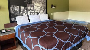 A hotel room with a large bed, a nightstand, a wall-mounted lamp, and a bathtub.