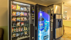 A vending machine with snacks and a drink dispenser in a commercial setting. - AmericInn by Wyndham Streator (Streator)