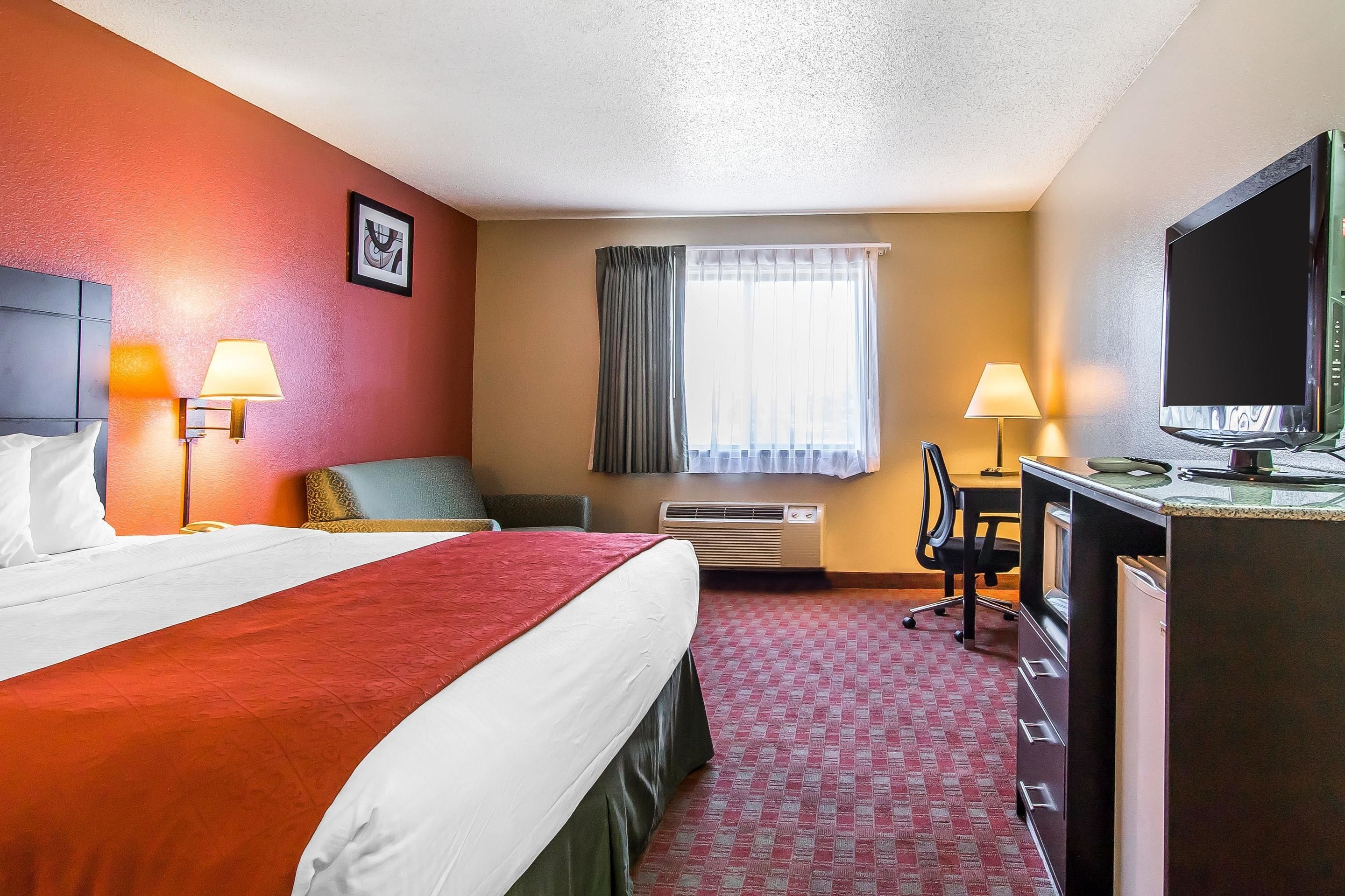 Een hotelkamer met een bed, bureau, stoel en televisie.