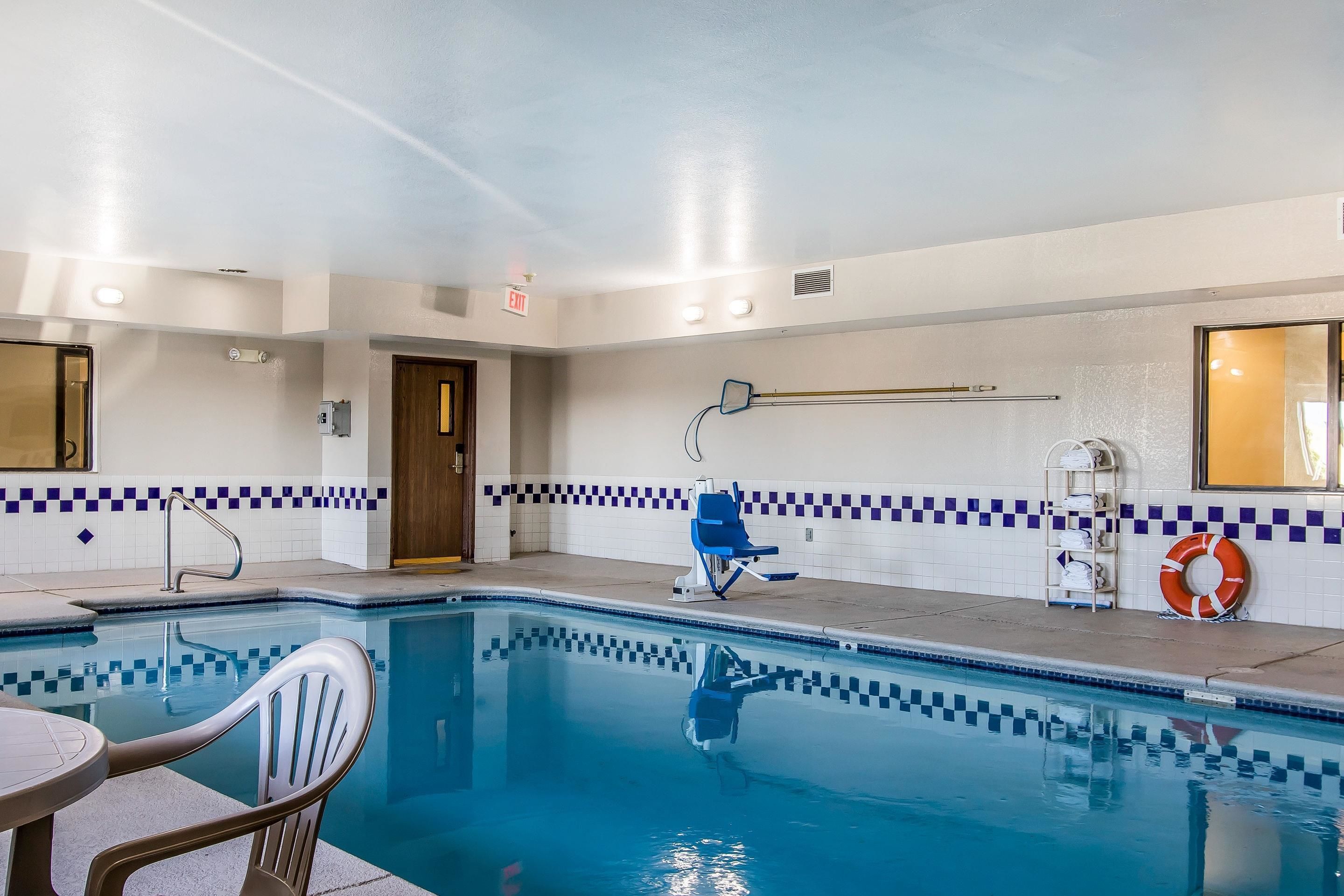 Un espace piscine bordé de carreaux, avec une bouée de sauvetage et une chaise.