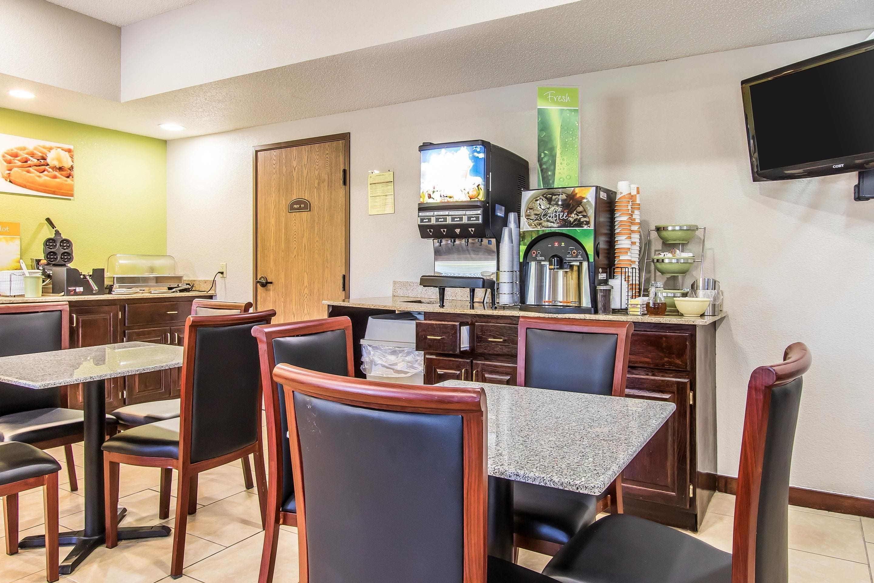 Un restaurante con una cafetera, un televisor y una pizarra de menú.