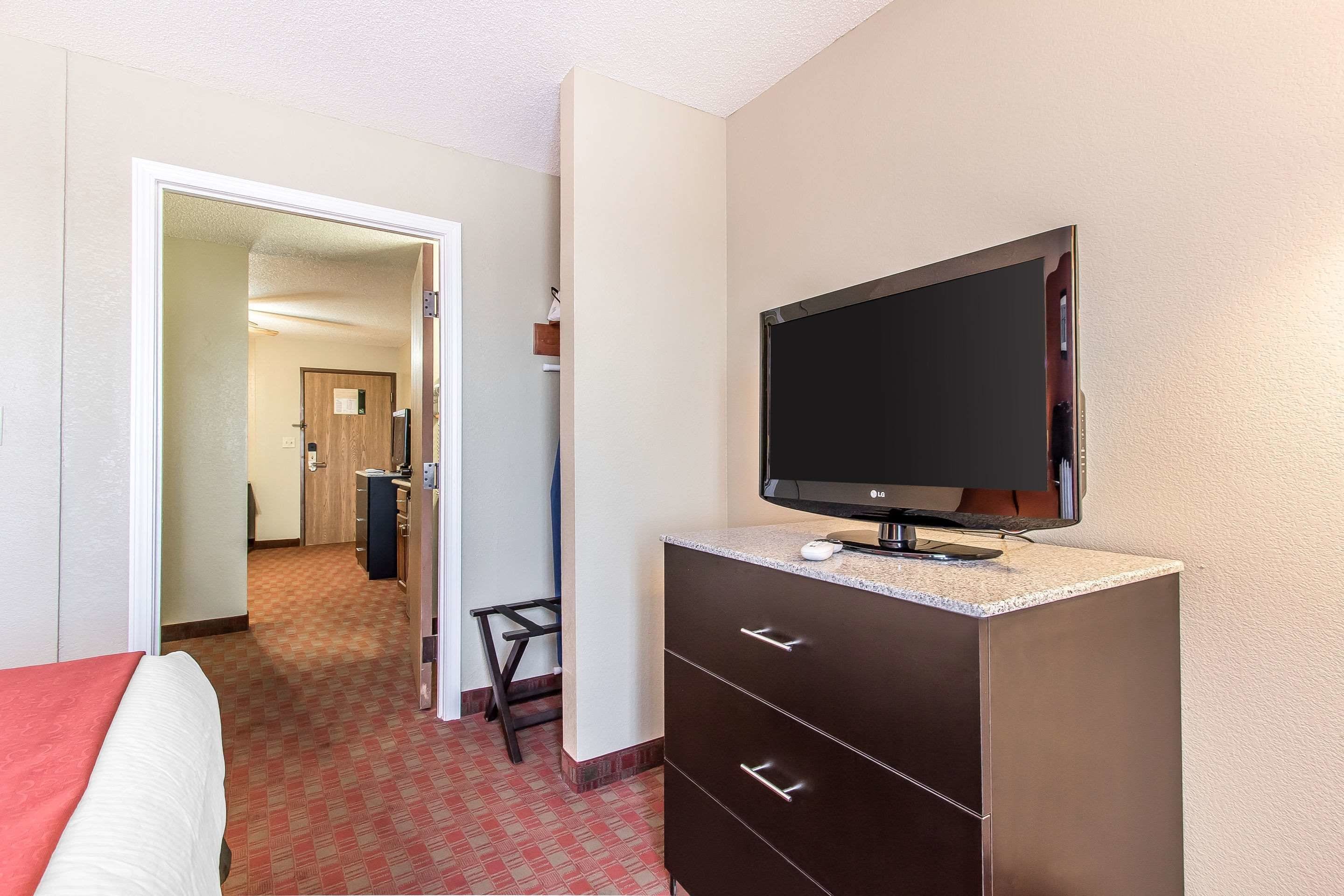 A hotel room with a bed, a TV on a cabinet, a desk, and a chair.