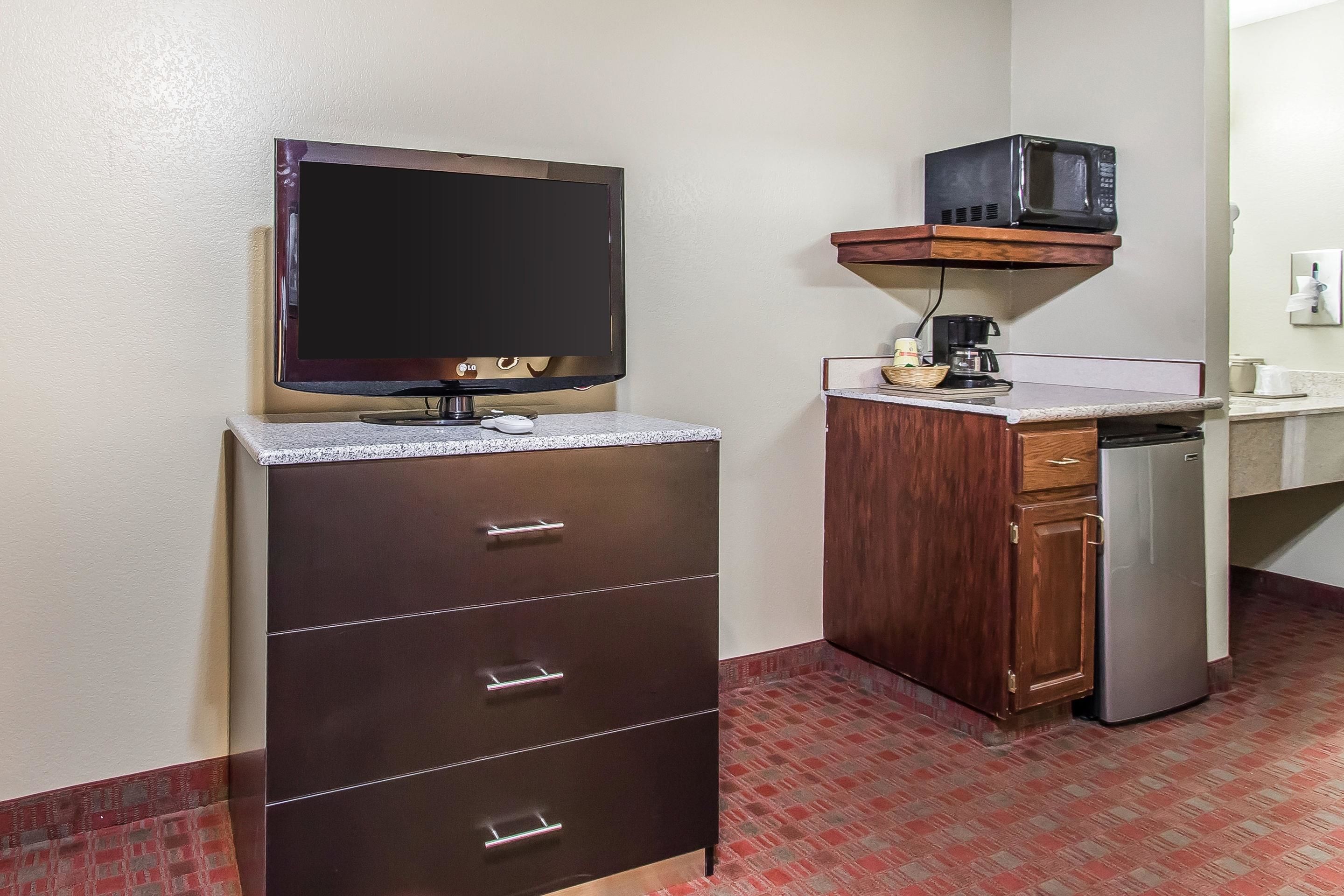 A compact kitchenette with a flat-screen TV, a microwave, a coffee maker, and a refrigerator.