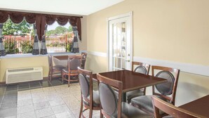 A dining area with a table and chairs, a door, and a view of a fenced outdoor area. - Super 8 by Wyndham Jasper (Jasper)