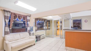 A living room with a sofa, a coffee table, and a sliding glass door leading to a kitchen area. - Super 8 by Wyndham Jasper (Jasper)
