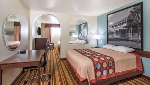 Habitación de hotel con cama, escritorio, silla y dos espejos.
