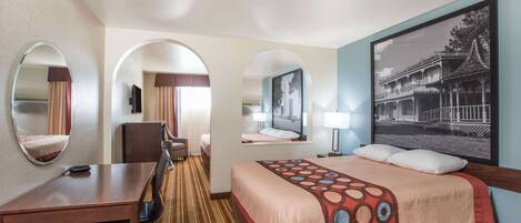 Habitación de hotel con cama, escritorio, silla y dos espejos.