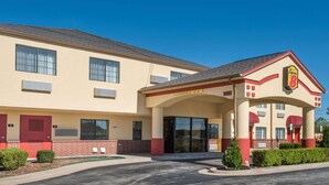 Un motel con fachada color beige, detalles en rojo y un cielo azul despejado.