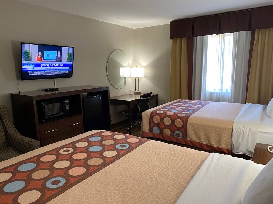 Una habitación de hotel con dos camas, un escritorio, un televisor y un minibar.