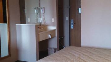 Habitación de hotel con dos camas, un escritorio pequeño, un espejo y una puerta.