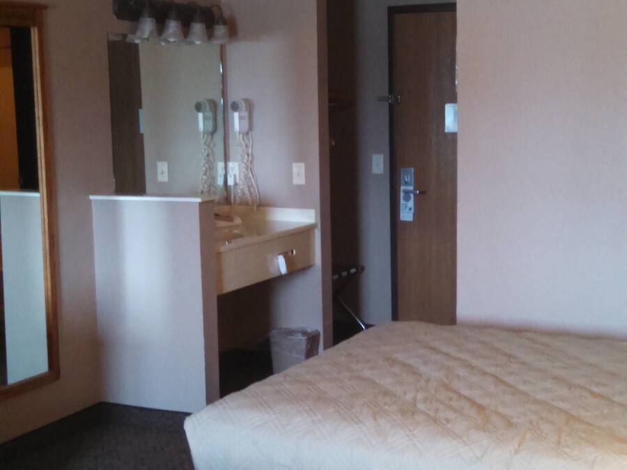 Habitación de hotel con dos camas, un escritorio pequeño, un espejo y una puerta.