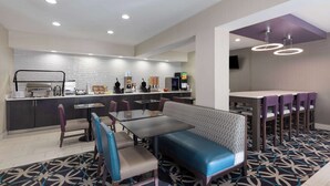 A modern hotel dining area with a bar, seating, and a patterned floor.