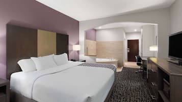 Una habitación de hotel moderna con una cama grande, un escritorio, un televisor, un baño con bañera y ducha.