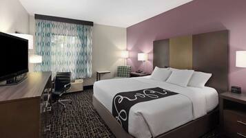 A hotel room with a large bed, a desk with a chair, a TV, and two bedside lamps.