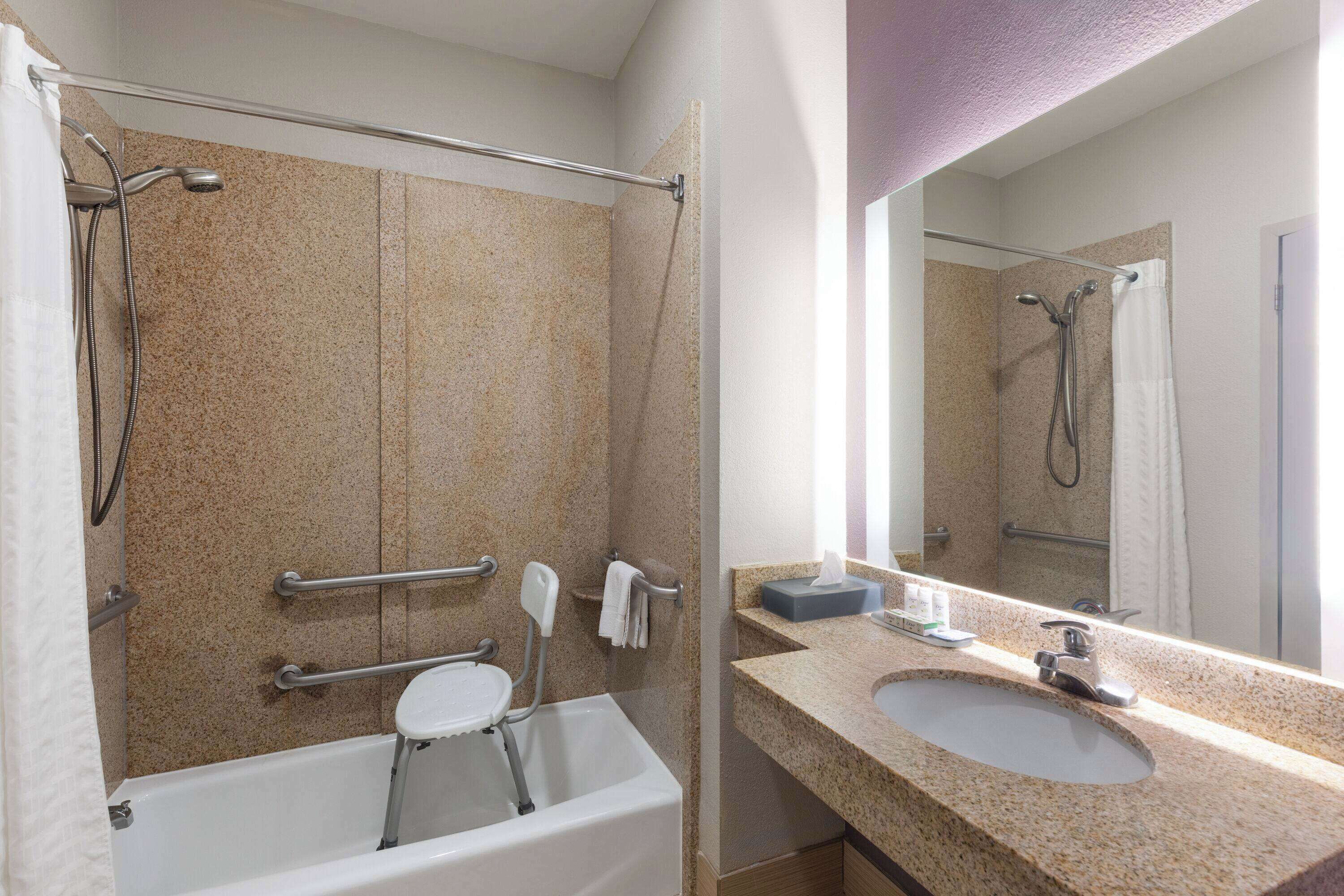 A bathroom with a bathtub, a sink, a mirror, and a shower area.
