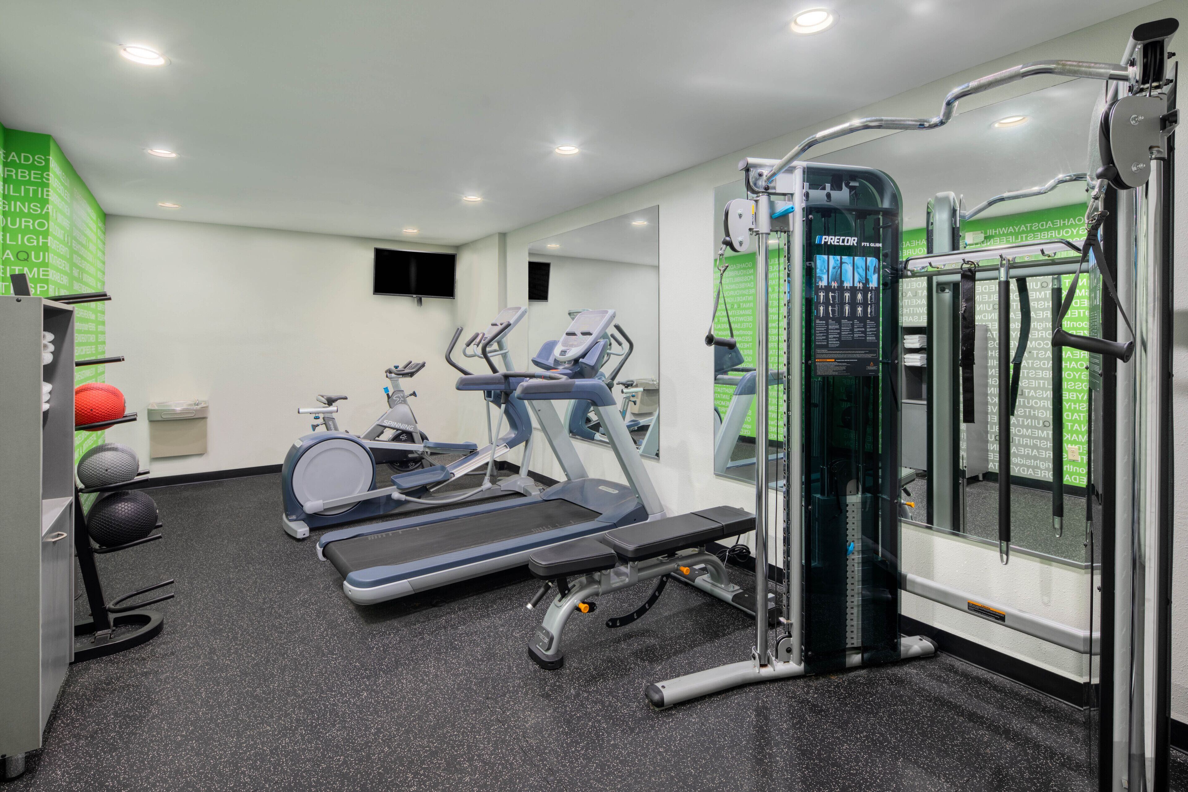 Ein Fitnessstudio mit Laufbändern, Crosstrainern und Gewichten.