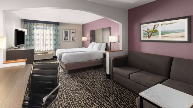 A hotel room with a bed, a sofa, a desk, and a TV.